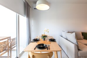 Ein Essbereich mit Tisch für zwei Personen, einer Couch und einem Topf mit einer Orchidee.