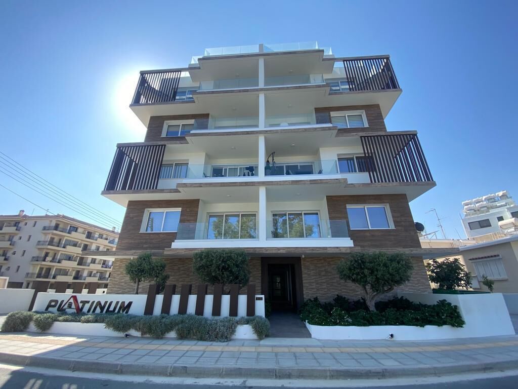 A multi-story residential building with balconies, a sign reading 'PLATINUM,' and a clear sky.