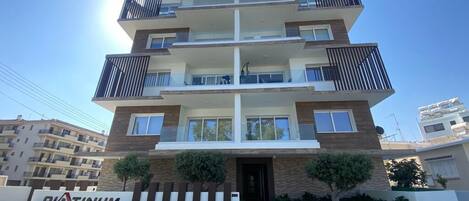 A multi-story residential building with balconies, a sign reading 'PLATINUM,' and a clear sky.
