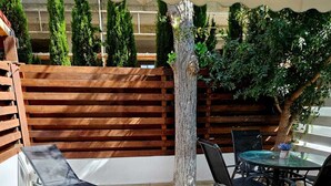 An outdoor patio with a table and chairs, a lounge chair, and a cactus planter. - Studio in the heart of Paphos (Pafos)