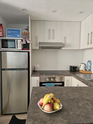 A modern kitchen with stainless steel appliances, a microwave, and a fruit bowl on the counter. - Studio in the heart of Paphos (Pafos)