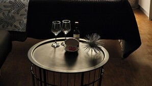 A hotel room with a bed, a round table with glasses and a bottle, and a view through a window with curtains. - Studio in the heart of Paphos (Pafos)