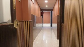 A corridor with a polished floor, wooden paneling on the walls, and a door with a brass handle. - Hotel Church View (Kolkata)