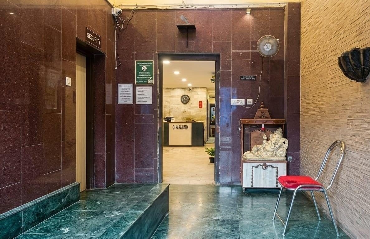 Un vestíbulo con un mostrador de seguridad, un letrero de banco, una estatua y una silla roja.