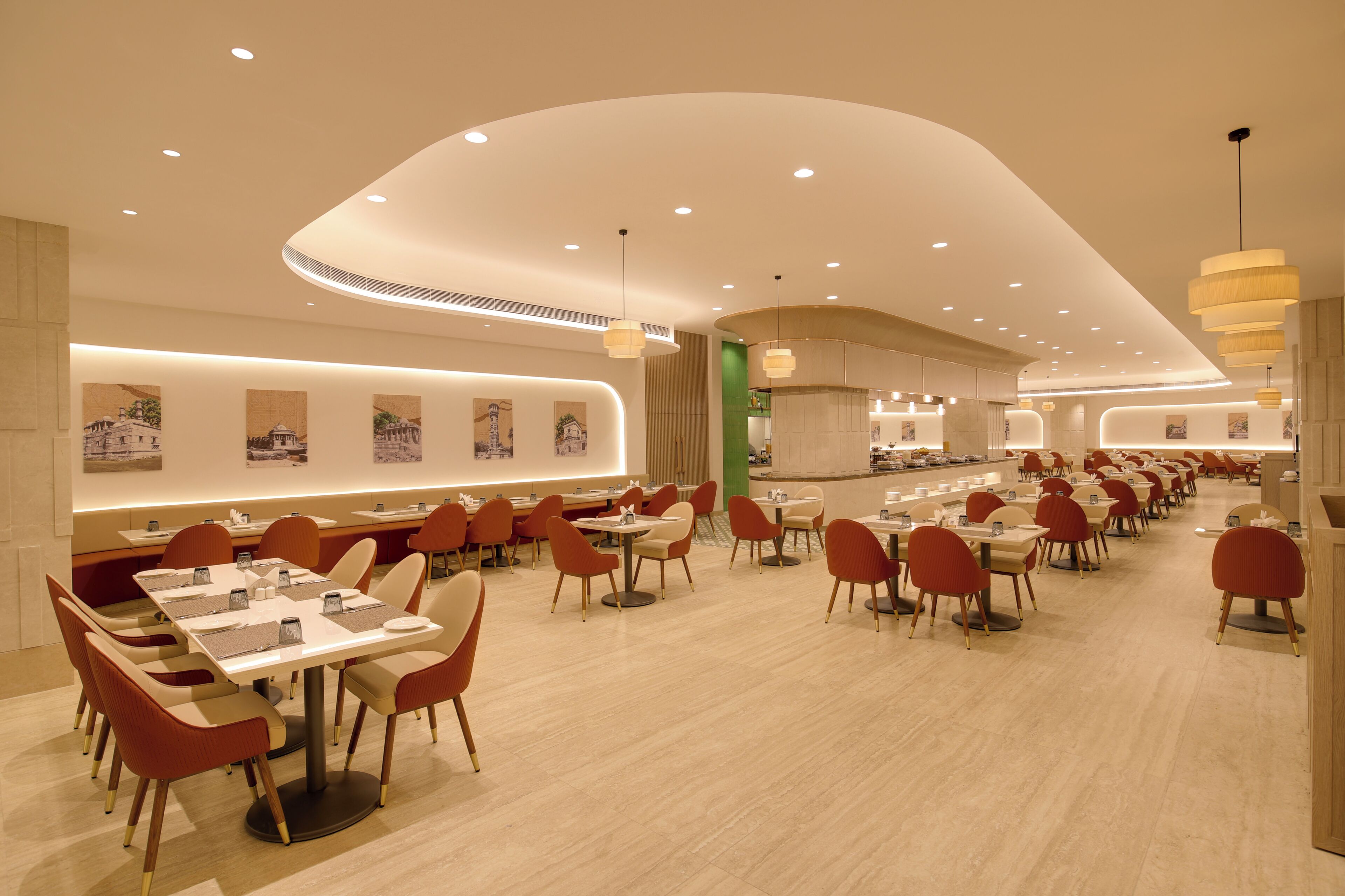 A spacious restaurant with multiple dining tables and chairs, a curved ceiling design, and wall-mounted artwork.