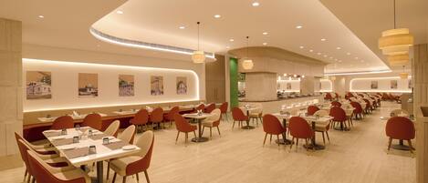 A spacious restaurant with multiple dining tables and chairs, a curved ceiling design, and wall-mounted artwork.