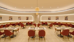 A spacious dining area with round tables and chairs, recessed lighting, and wall art. -  Lemon Tree Hotel, Bharuch (Bharuch)