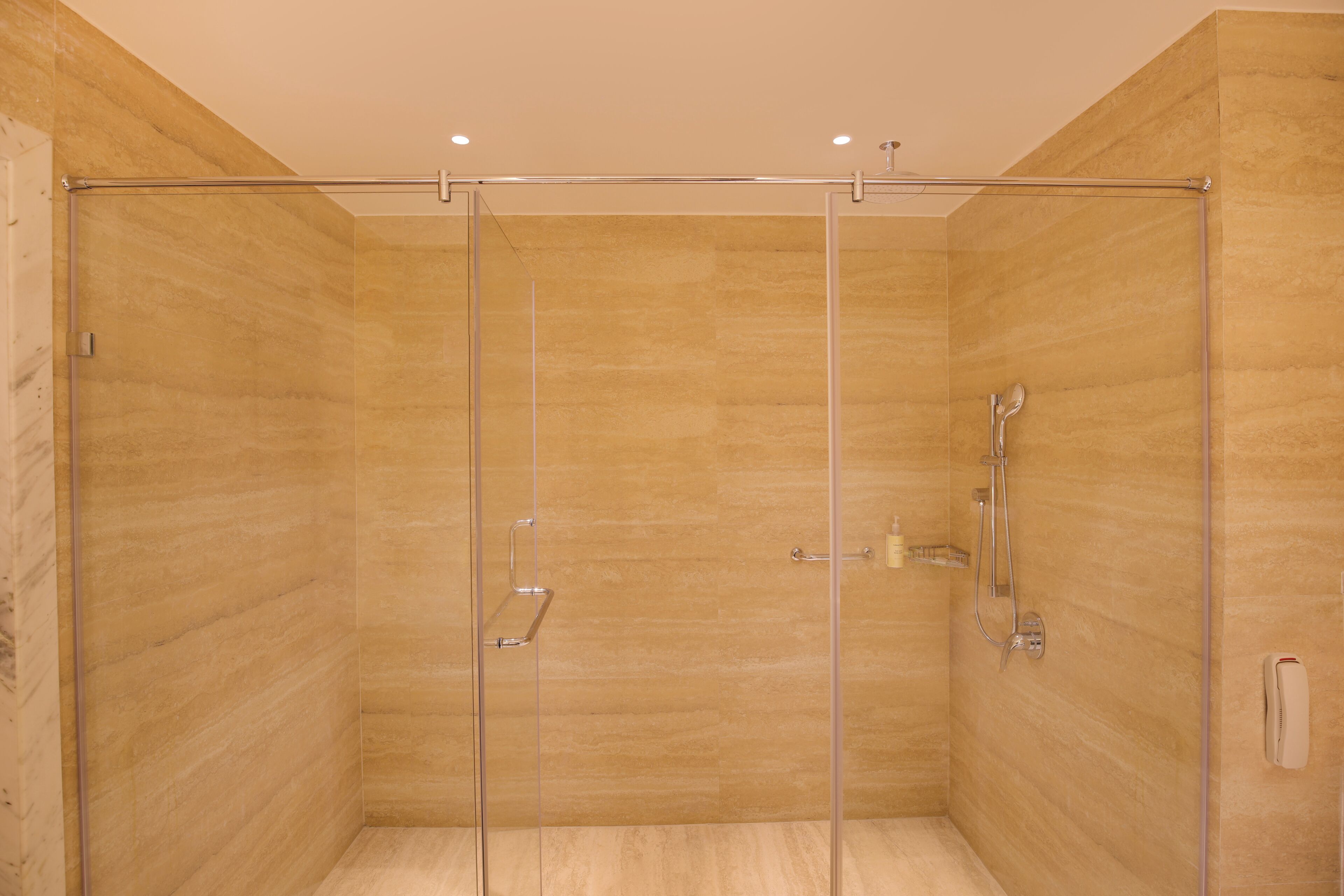 Cabina de ducha con paredes de vidrio, ducha de mano y grifo de mano.