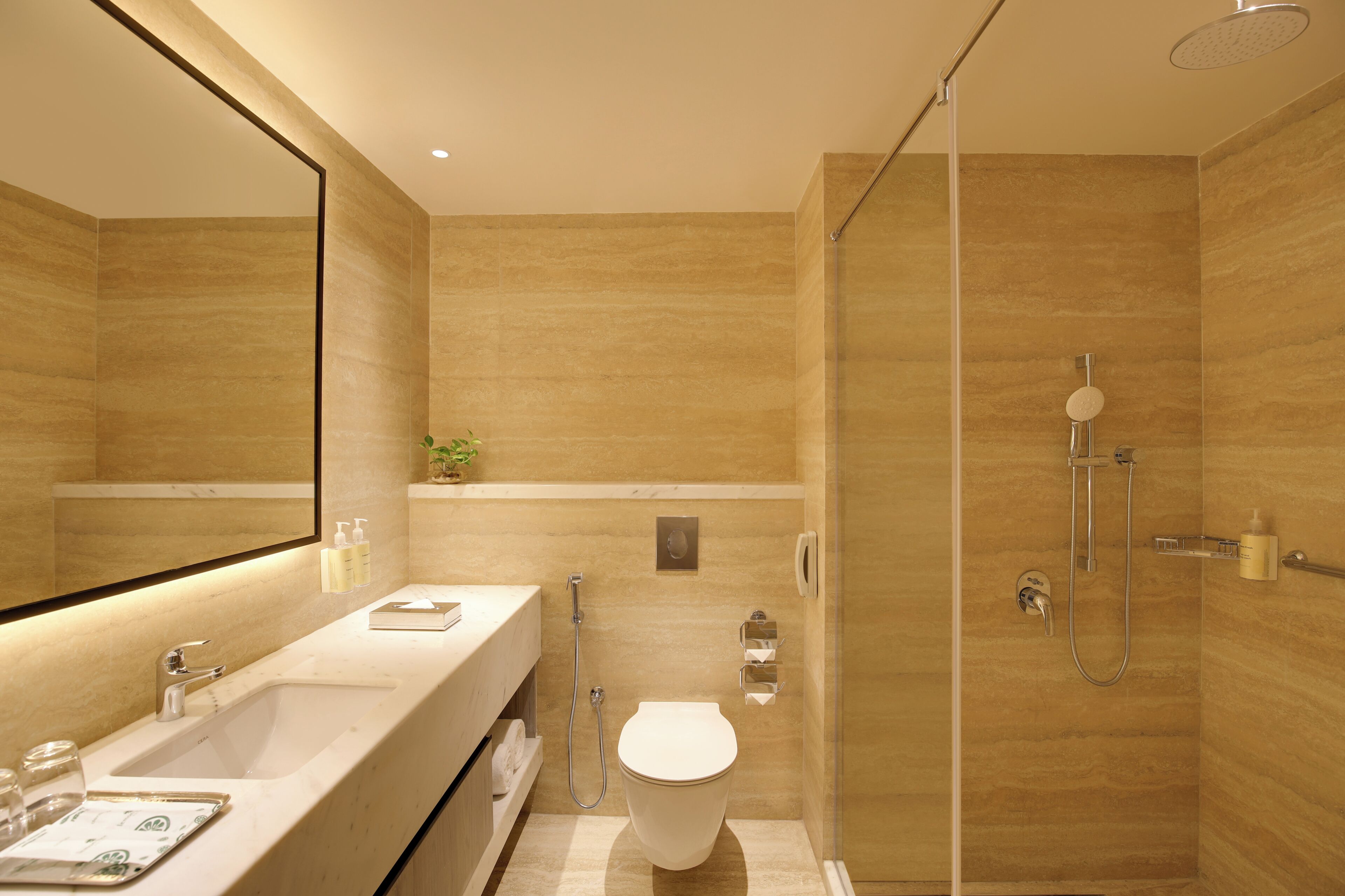 Une salle de bain moderne avec un grand miroir, un lavabo, des toilettes et un espace douche.