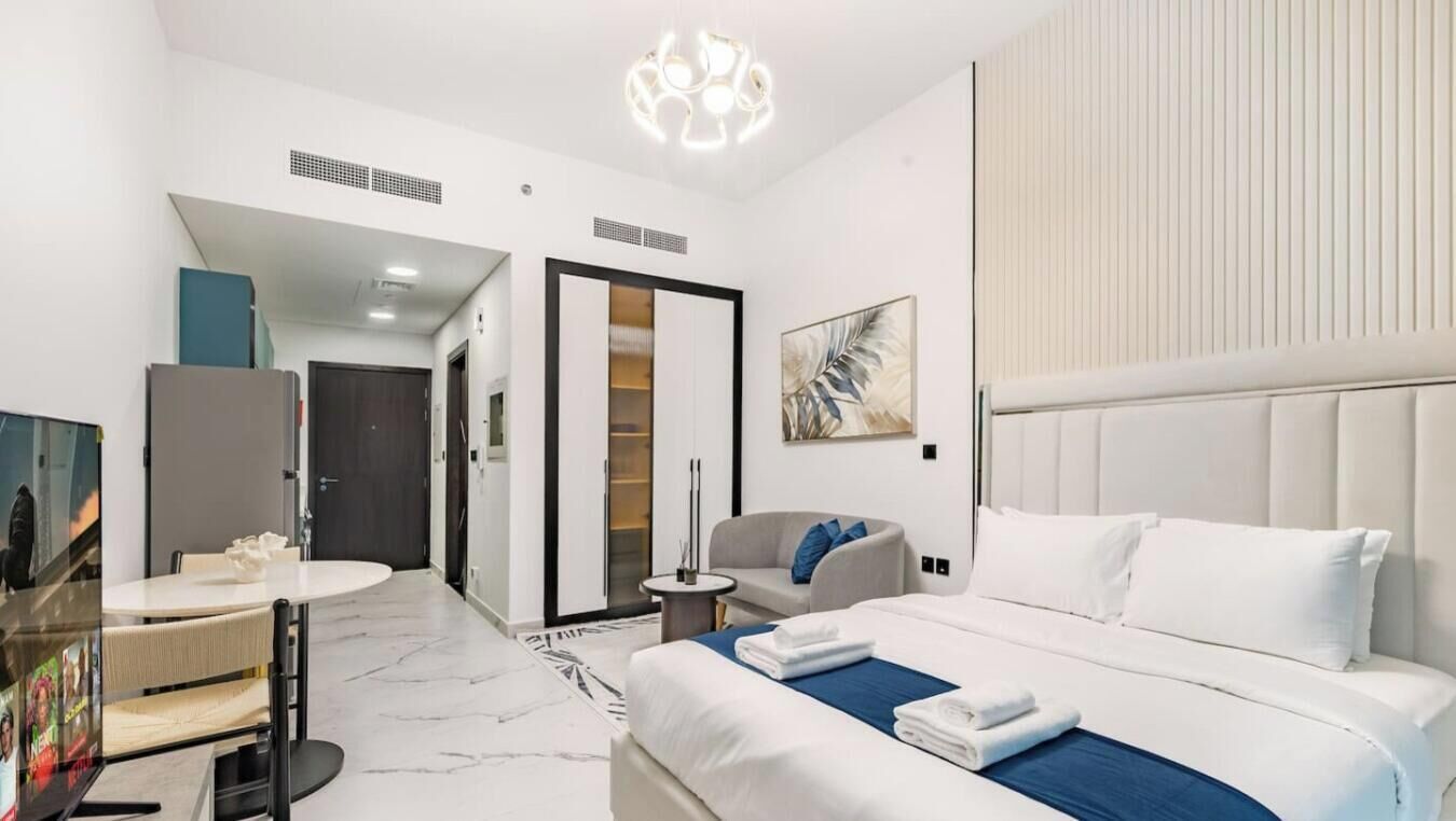 Ein modernes Hotelzimmer mit einem großen Bett, einer Sitzecke mit einer Couch, einem kleinen runden Tisch und einem Fernseher.