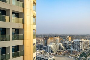 A high-rise building with multiple floors and large windows, overlooking a cityscape with various buildings and a clear sky. - Peaceful Studio | Opalz by Danube | BMS (Dubai)