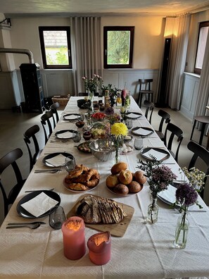 Ein Esstisch, gedeckt für eine Mahlzeit, mit verschiedenen Speisen, Brot und Kerzen.