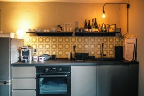 Eine Küche mit einer Kaffeemaschine, einem Backofen und Weinflaschen auf der Arbeitsplatte.