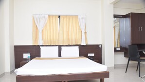 Une chambre d’hôtel avec un lit, des tables de chevet, une chaise et une armoire.