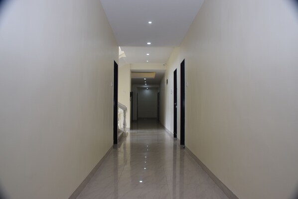 A corridor with a polished floor, white walls, and doors on both sides.