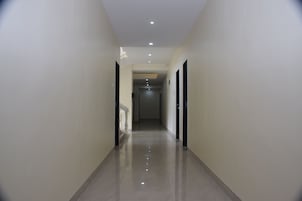 Um corredor com piso lustroso, paredes brancas e portas em ambos os lados.
