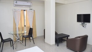Un salon moderne doté d’un téléviseur à écran plat, d’une table à manger en verre et d’un canapé confortable.