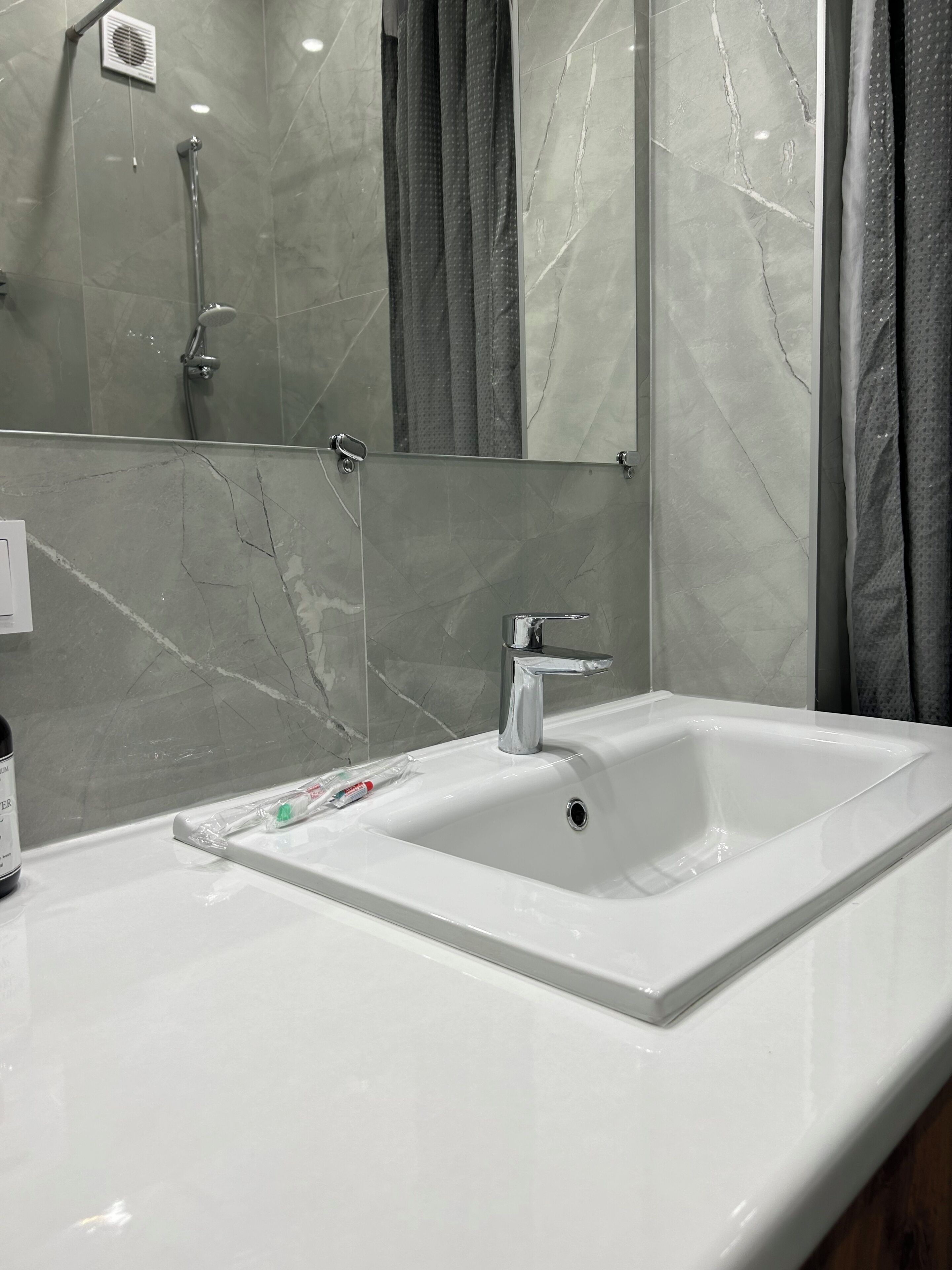 Un baño con lavamanos blanco, un espejo y una ducha.