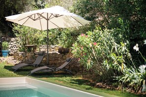 A pool area with lounge chairs and an umbrella. - Romantic Troglodyte Suite near Sarlat in the Dordogne (Vitrac)