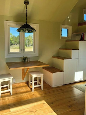A compact kitchen with a wooden countertop, white cabinetry, and a hanging light fixture.