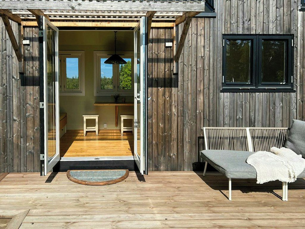 A wooden exterior with a sliding door leading to an interior space with a bench and a table.
