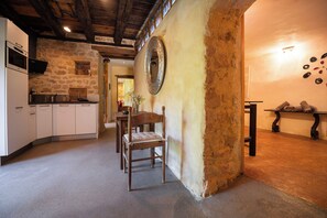 A rustic kitchen with stone walls, wooden furniture, and a large mirror. - Troglodyte Cottage with Private Pool near Sarlat (Vitrac)