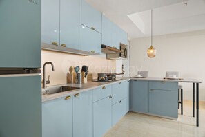 A modern kitchen with light blue cabinets, stainless steel appliances, and a central island with seating. - Ravora by Kozystay - Sungkono (Surabaya)