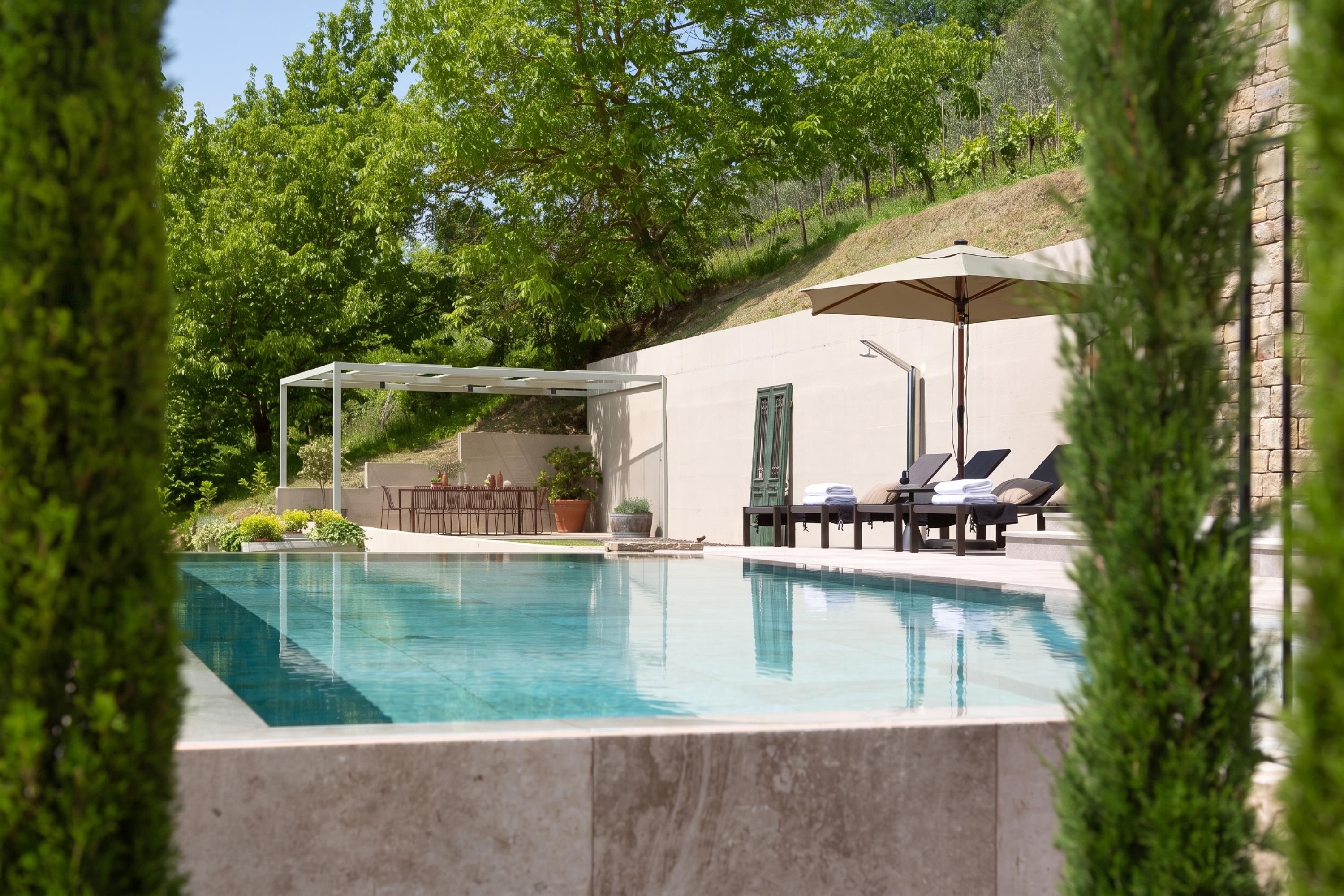 Una piscina con lettini e un pergolato, immersa nel verde.