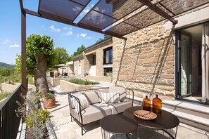 An outdoor patio area with a stone wall, a covered seating area with a sofa and a table, and a large tree. - Villa Panorama Del Tartufo (Buzet)