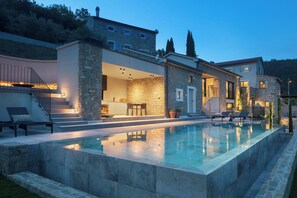 Uma casa moderna com piscina, paredes de pedra e área de estar externa.