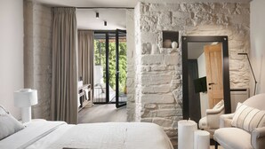 A bedroom with a stone wall, a bed with a magazine, a chair, and a view of the outdoors. - Villa Panorama Del Tartufo (Buzet)