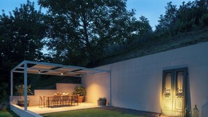 A modern outdoor patio with a table and chairs, surrounded by a low wall and a covered seating area. - Villa Panorama Del Tartufo (Buzet)
