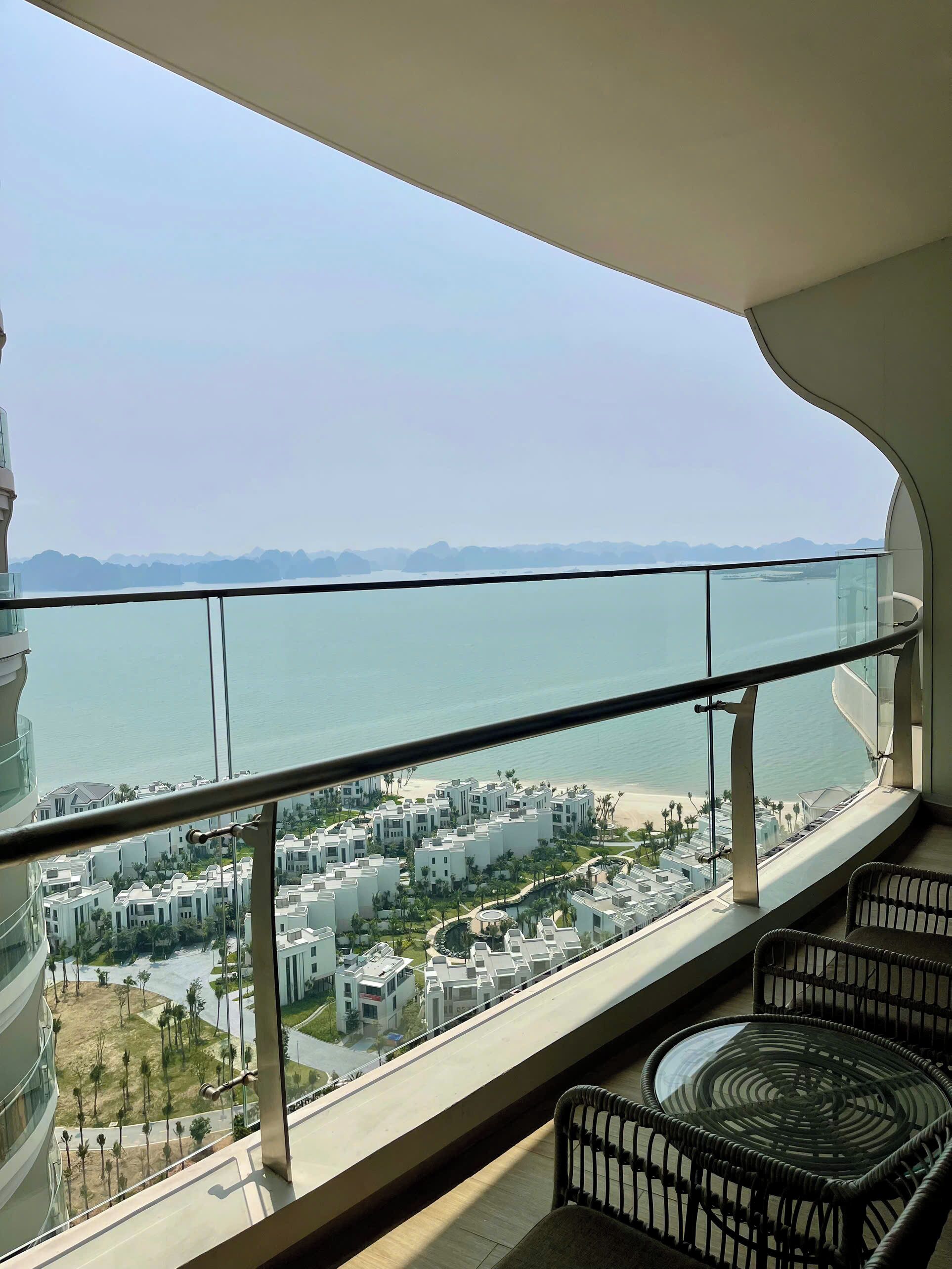 A balcony with a view of a beach, a pool, and a residential area.