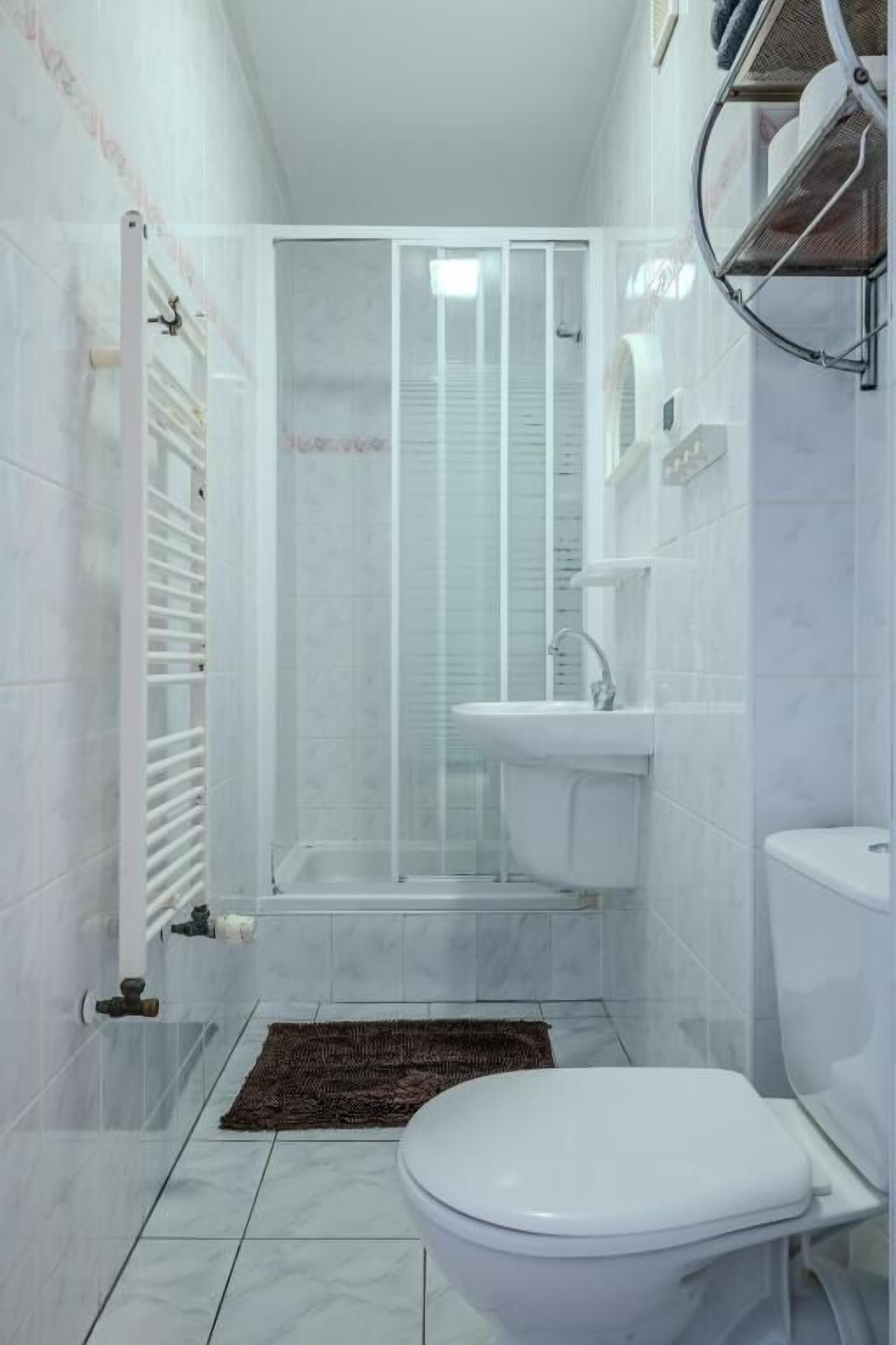 A bathroom with a toilet, sink, and shower enclosure.