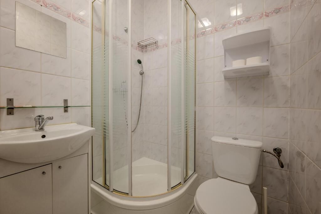 Ein Badezimmer mit einer Duschkabine, einem weißen Waschbecken und einer Toilette.