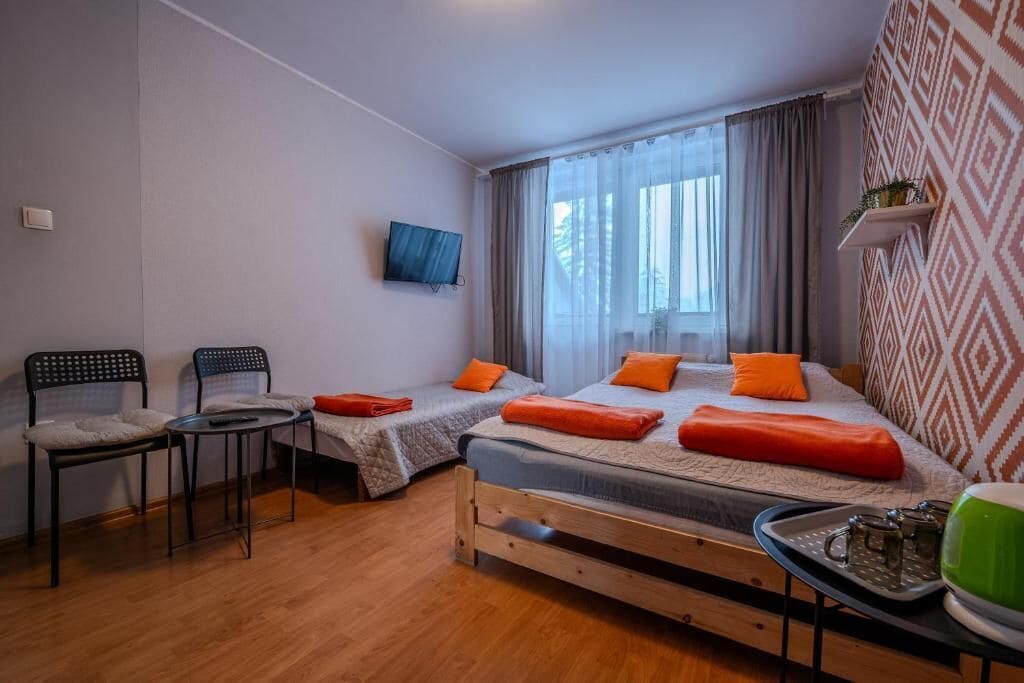 Un dormitorio con dos camas, televisión, una mesita y sillas.