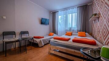 Un dormitorio con dos camas, televisión, una mesita y sillas.
