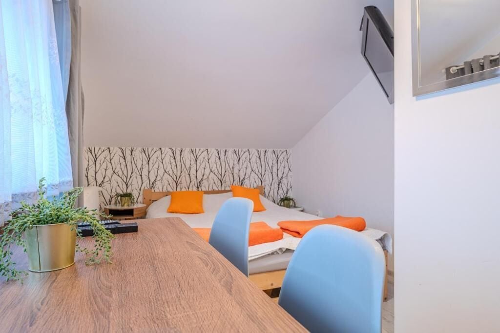 Un dormitorio con cama, una mesita de noche con una planta y un televisor montado en la pared.