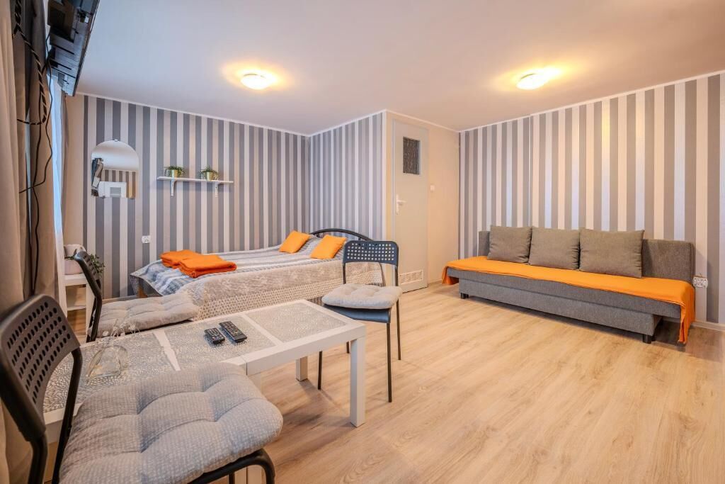 A room with two beds, a sofa, a dining table with chairs, and striped walls.