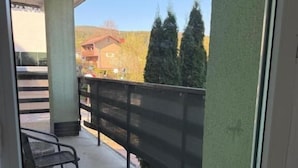 A balcony with a metal railing, a chair, and a concrete floor.