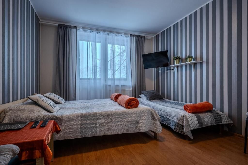 Una habitación de hotel con dos camas, televisión y ventana con cortinas.