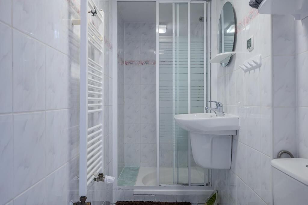 A bathroom with a glass-enclosed shower, a white sink, and a mirror on the wall.