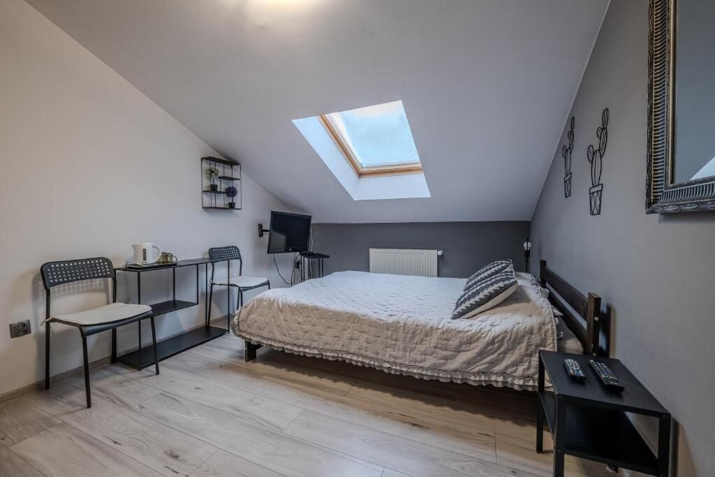 Un dormitorio con tragaluz, cama, escritorio, silla y televisión.