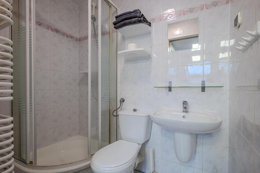 Un baño con ducha de vidrio, inodoro y lavamanos.