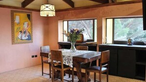 Un comedor con una mesa y sillas de madera, un florero con flores y un cuadro en la pared.