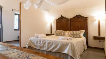 A bedroom with a large bed, two bedside tables, a nightstand, a patterned rug, and a window with curtains.