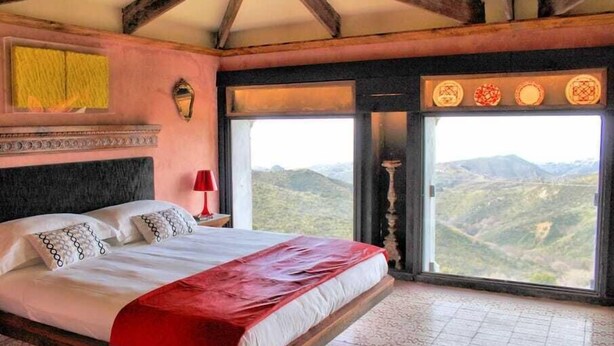 Un dormitorio con una cama grande, vistas a la montaña y una lámpara roja.