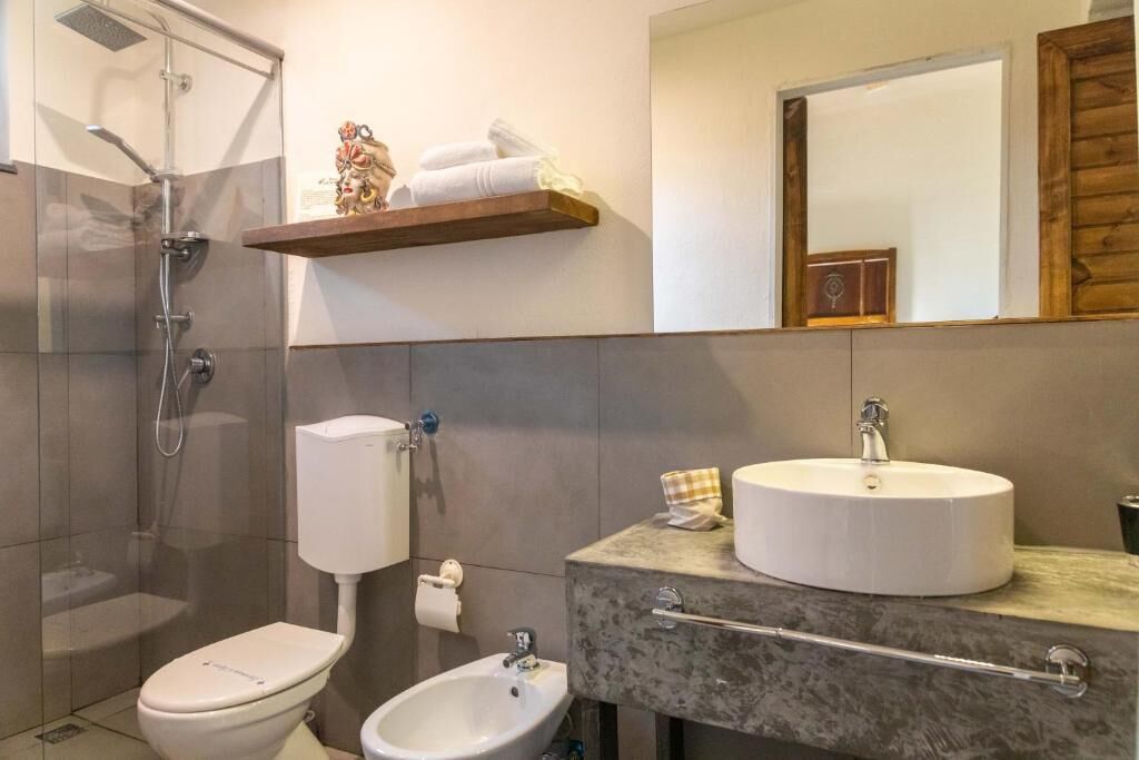 Un bagno con doccia, toilette, bidet e lavabo con specchio.