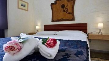 Una camera d'albergo con un letto rifatto, due lampade ai comodini e un'opera d'arte appesa al muro.