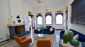 Un salón con chimenea, sofás y cactus.